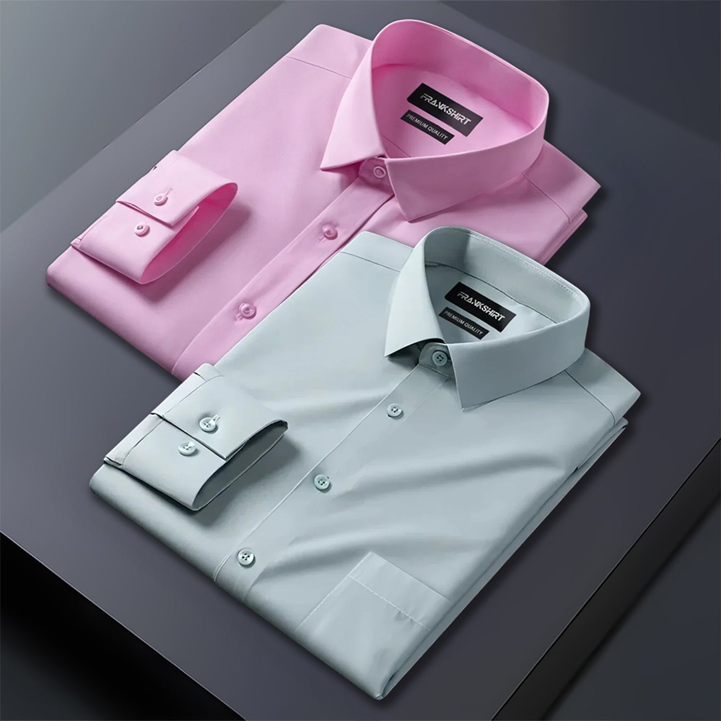 Two folded dress shirts, one pink and one light blue, on a dark surface.