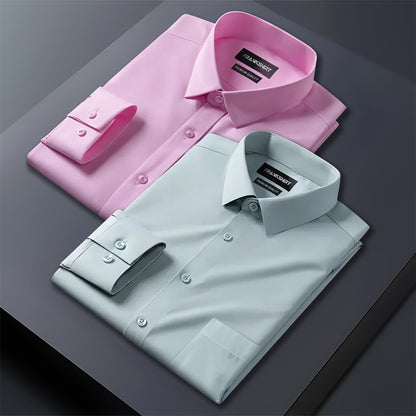 Two folded dress shirts, one pink and one light blue, on a dark surface.